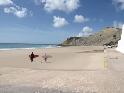 two people walking on the beach with their surfboards at Sea Studio Apartment in Budens