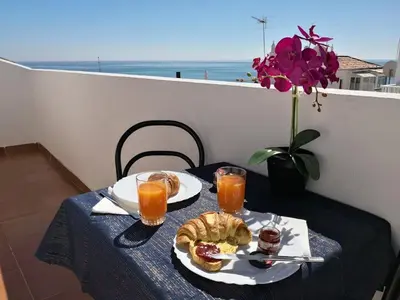 a table with two plates of food and two glasses of orange juice at Sea Studio Apartment in Budens