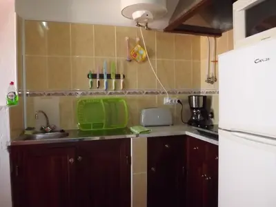 a small kitchen with a sink and a refrigerator at Sea Studio Apartment in Budens