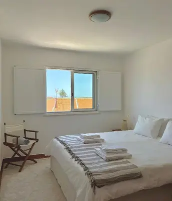 a white bedroom with a bed and a window at Casa Sul in Sagres