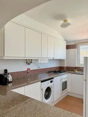 a kitchen with white cabinets and a washer and dryer at Casa Sul in Sagres