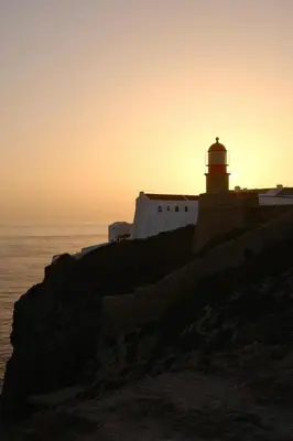 a lighthouse on a cliff near the ocean at sunset at Casa Sul in Sagres