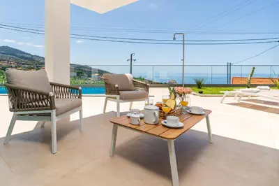a patio with two chairs and a coffee table with a view at Villa das Neves in Estreito da Calheta
