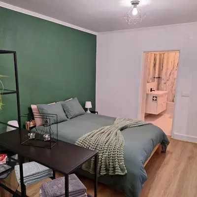 a green bedroom with a bed and a table at Casa das Grutas in São Vicente