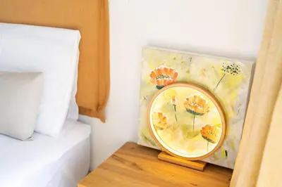a clock on a table next to a bed at Funchal Bay Apartment by Amazing Madeira in Funchal