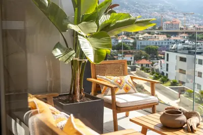a chair and a potted plant on a balcony at Funchal Bay Apartment by Amazing Madeira in Funchal