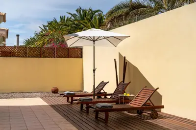 two chairs and a table with an umbrella on a patio at Moradia Felicidade Rocha PXO by An Island Apart in Porto Santo