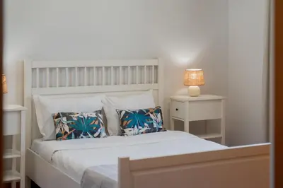 a bedroom with a white bed with pillows and a lamp at Moradia Felicidade Rocha PXO by An Island Apart in Porto Santo