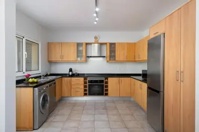 a kitchen with wooden cabinets and a stainless steel refrigerator at Moradia Felicidade Rocha PXO by An Island Apart in Porto Santo
