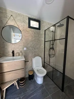 a bathroom with a toilet and a stone wall at The Green Valley House II in São Vicente