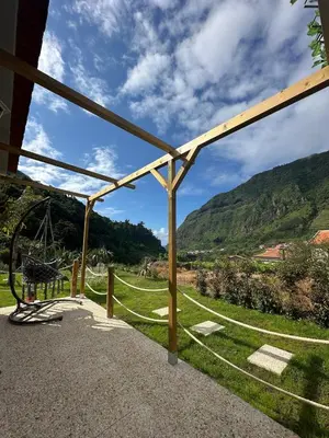 a garden with a building and a hill in the background at The Green Valley House II in São Vicente