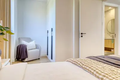 a white bedroom with a bed and a chair at The Place Funchal View, a Home in Madeira in Funchal