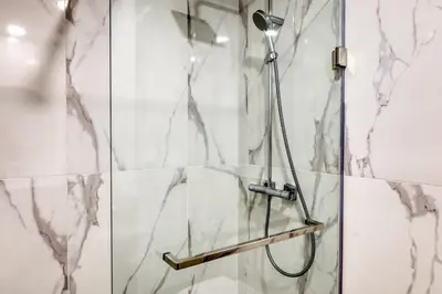 a shower in a bathroom with marble walls at The Place Funchal View, a Home in Madeira in Funchal
