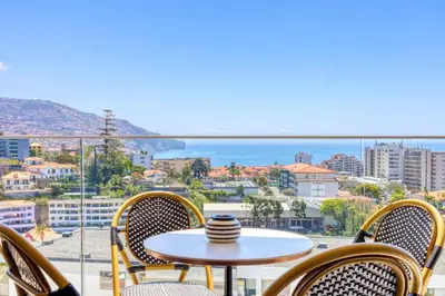 a table and chairs on a balcony with a view of the city at The Place Funchal View, a Home in Madeira in Funchal