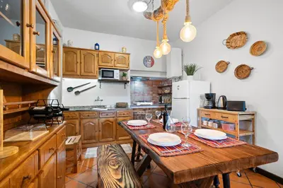 a kitchen with wooden cabinets and a wooden table with chairs at Casa do Vale 13 - Ribeiro Frio in São Roque