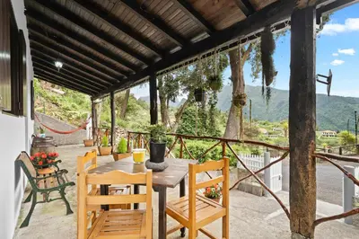 a table and chairs on a patio with a view at Casa do Vale 13 - Ribeiro Frio in São Roque