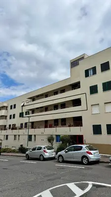 two cars parked in a parking lot in front of a building at Nazaré Stay in Funchal