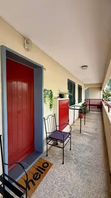 a porch with a red door and a chair at Nazaré Stay in Funchal