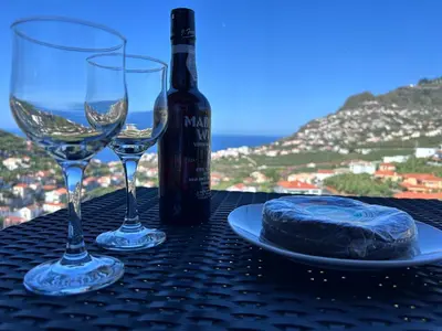 a table with two wine glasses and a bottle of wine at Saraiva Hills Ocean View Penthouse in Câmara de Lobos