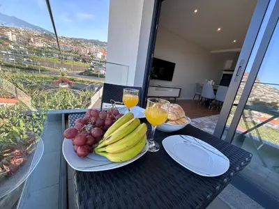 a table with plates of fruit and glasses of orange juice at Saraiva Hills Ocean View Penthouse in Câmara de Lobos