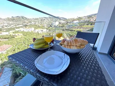 a table with a plate of bread and glasses of wine at Saraiva Hills Ocean View Penthouse in Câmara de Lobos