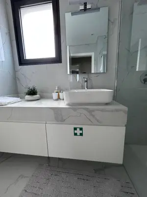 a white bathroom with a sink and a mirror at Saraiva Hills Ocean View Penthouse in Câmara de Lobos