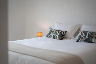 a white bed with pillows and a lamp on it at White Apartment in Funchal