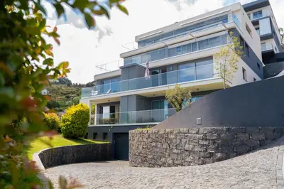 an apartment building with a stone wall in front of it at White Apartment in Funchal