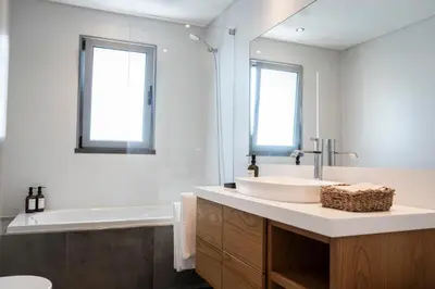 a bathroom with a sink and a tub and a mirror at White Apartment in Funchal