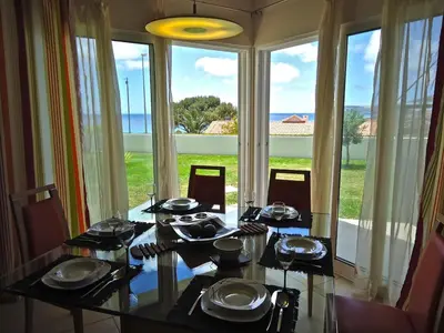 a dining room with a table with chairs and a large window at Golden Villa - Luxurious Beach Villa in Porto Santo