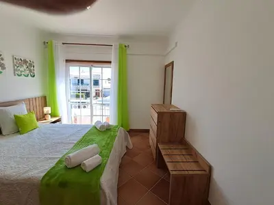 a bedroom with a large bed with green accents at Villa Praia Porto de Mós in Lagos
