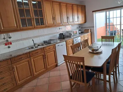 a kitchen with wooden cabinets and a table and chairs at Villa Praia Porto de Mós in Lagos