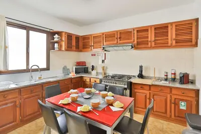 a kitchen with a red table with chairs in it at Vila Vitalia in Machico