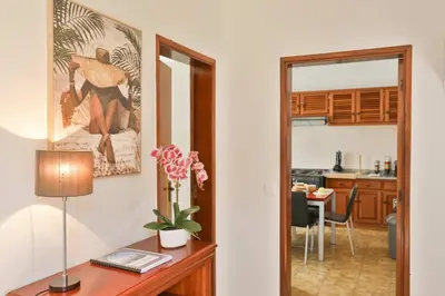 a room with a desk with a lamp and a kitchen at Vila Vitalia in Machico