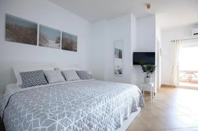 a white bedroom with a bed and a television at Beach View Lagos in Lagos