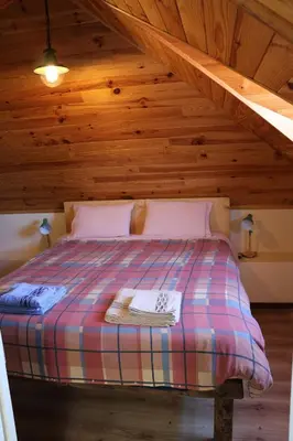a bedroom with a bed in a wooden attic at Quinta do Ribeiro Real in Câmara de Lobos