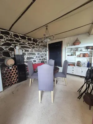 a dining room with a table and chairs and a stone wall at Quinta do Ribeiro Real in Câmara de Lobos