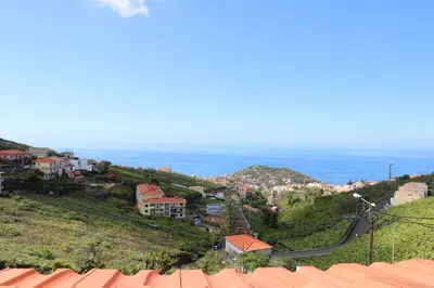 a town on a hill with the ocean in the background at Quinta do Ribeiro Real in Câmara de Lobos