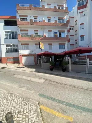 an empty street in front of a building with red umbrellas at MarLuz in Luz