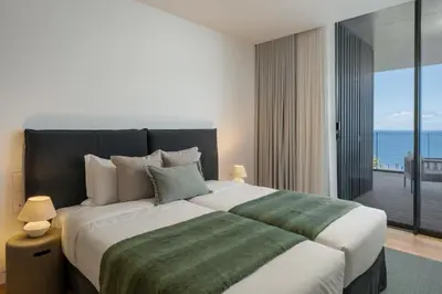 a bedroom with a large bed with a view of the ocean at Savoy Monumentalis V by An Island Apart in Funchal