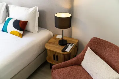 a room with a bed and a table with a lamp and a chair at Funchal Heart Studio in Funchal