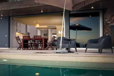 a patio with chairs and a table and an umbrella at Villa Fig Tree in Prazeres