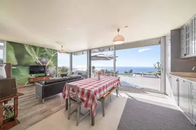 a living room with a table and a view of the ocean at Villa Fig Tree in Prazeres
