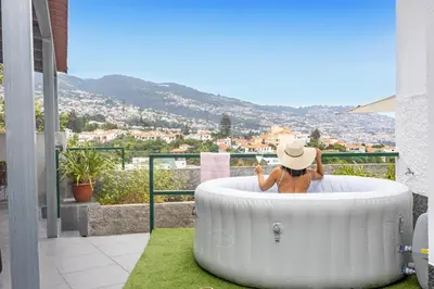 a person sitting in a bath tub on a balcony at Serenity View by YOUR KEY in Funchal