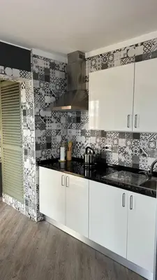 a kitchen with white cabinets and black counter tops at Grayscale Studio in Caniço
