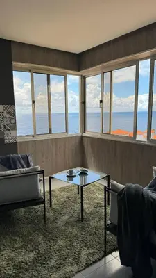 a living room with a table and a view of the ocean at Grayscale Studio in Caniço
