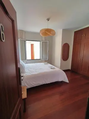 a bedroom with a white bed and a window at North Madeira Guesthouse in Seixal