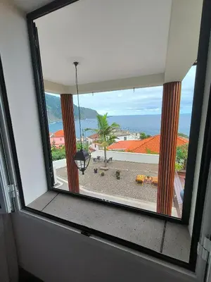 a window in a room with a view of the ocean at North Madeira Guesthouse in Seixal