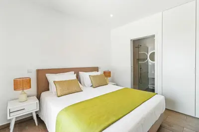 a white bedroom with a large bed with a yellow blanket at The Oceanfront Villa Luz VR114 in Luz
