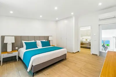 a bedroom with a large bed with blue pillows at The Oceanfront Villa Luz VR114 in Luz